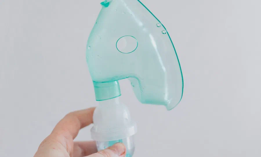 A hand holding a respiratory nebulizer mask
