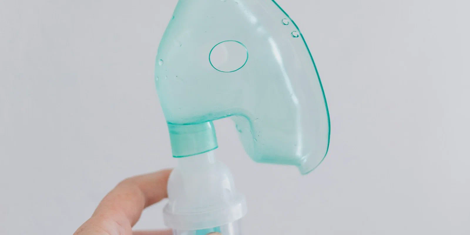 A hand holding a respiratory nebulizer mask