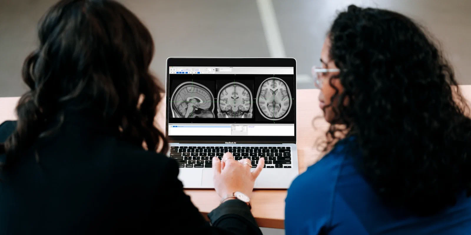 Two researchers examining brain images on a laptop
