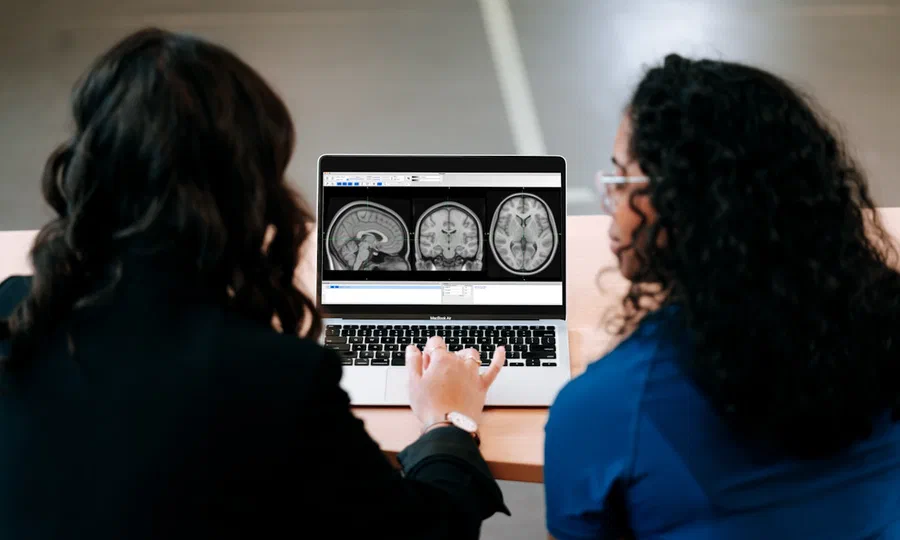 Two researchers examining brain images on a laptop