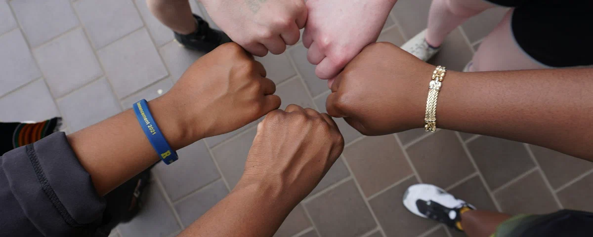 A diverse group joining their hands in a circle